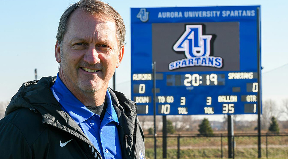 Don Beebe standing in front of the Aurora scoreboard.